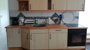 Una cocina con gabinetes de madera, cafetera, tostadora, pileta y lavavajillas.