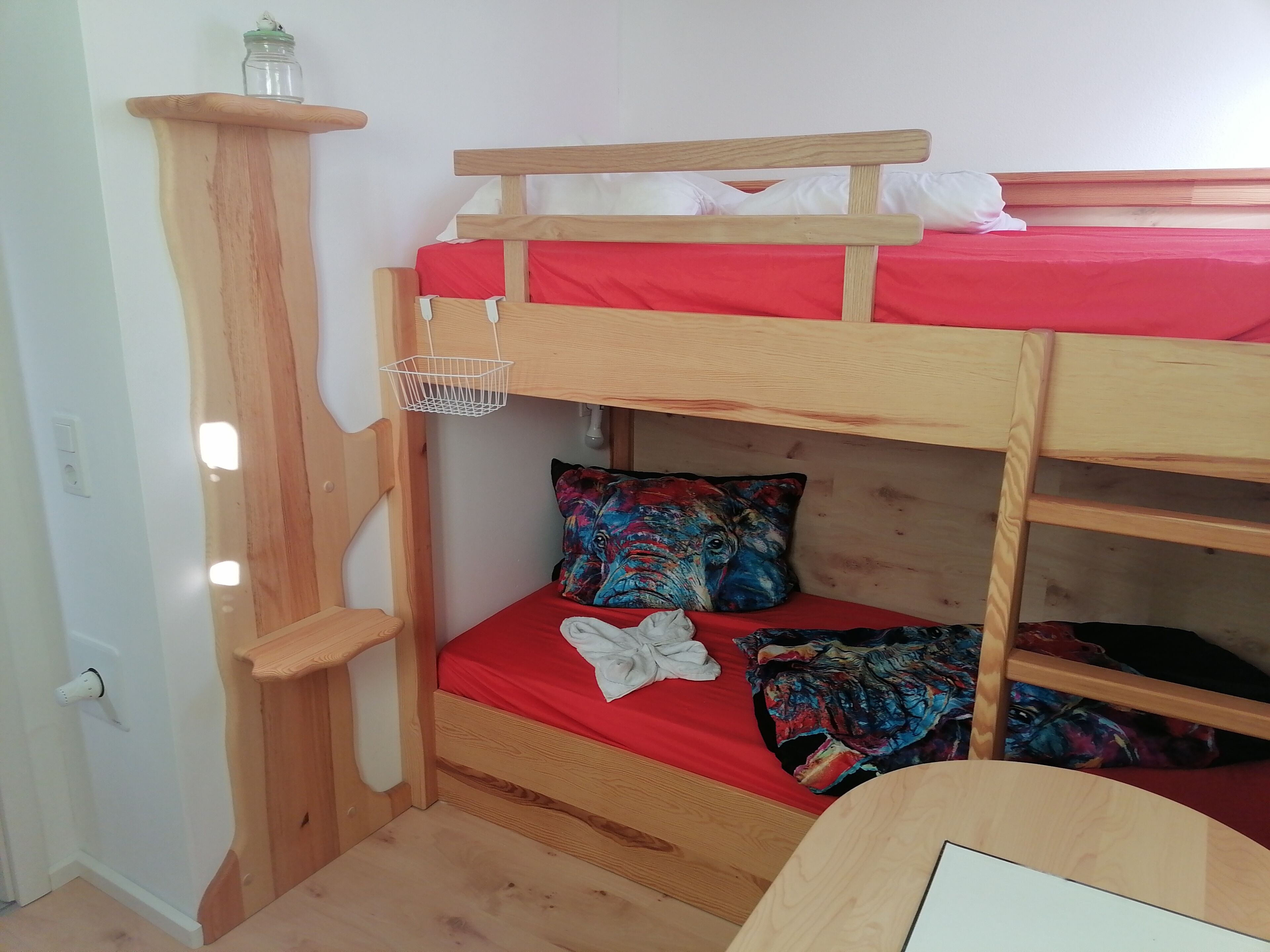 Un letto a castello con materasso rosso, una testiera in legno e un cuscino colorato.