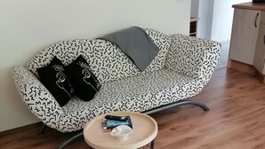 Un salón moderno con un sofá estampado, una mesita redonda con un cuenco, y un otoman complementario.