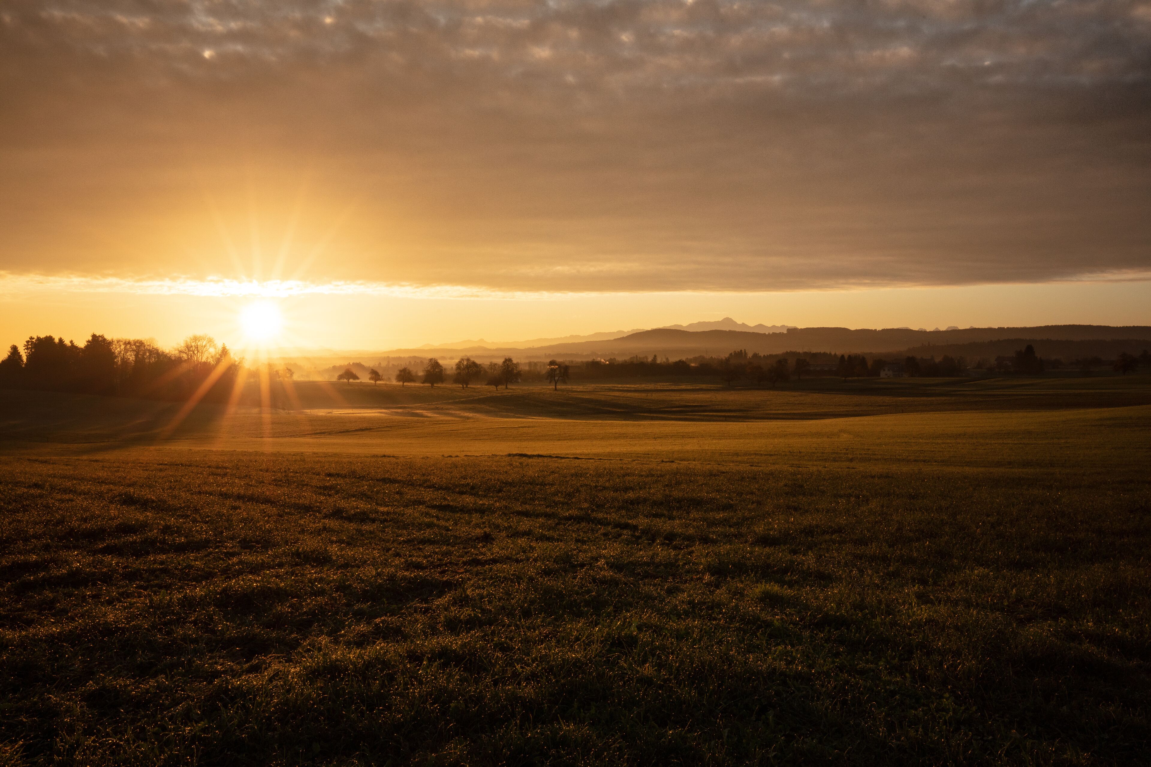 Un campo abierto y extenso con un atardecer en la distancia.
