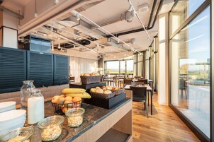 A modern breakfast area with a counter displaying bread, fruits, and beverages.