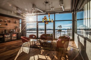 A modern living room with a large window, wooden flooring, and a variety of seating options.