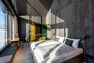 A modern bedroom with a large bed, a desk, and a chair.