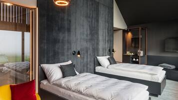 Un dormitorio moderno con dos camas, una silla amarilla e iluminación colgante.