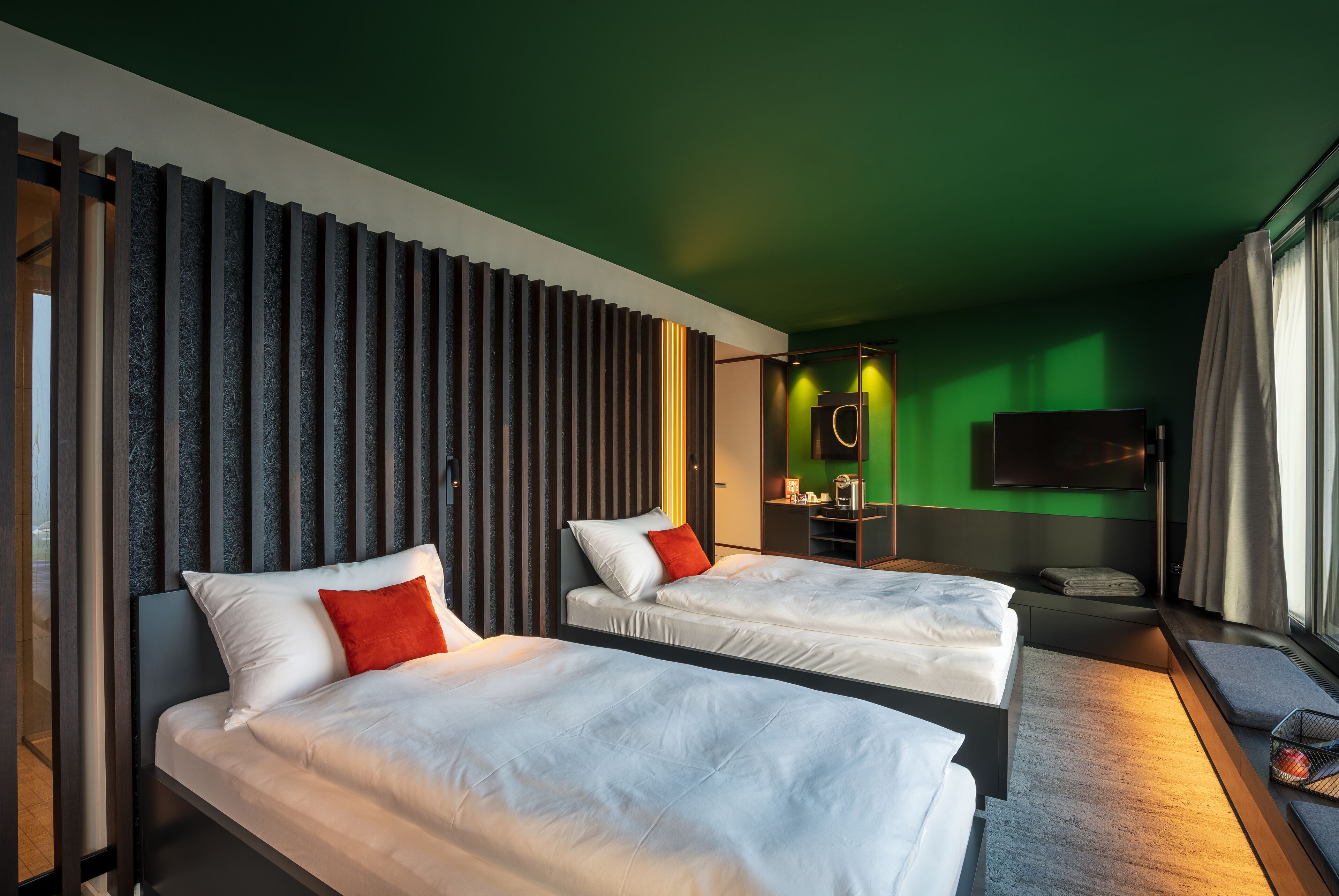 Une chambre d’hôtel avec deux lits, une télévision et un mur vert.
