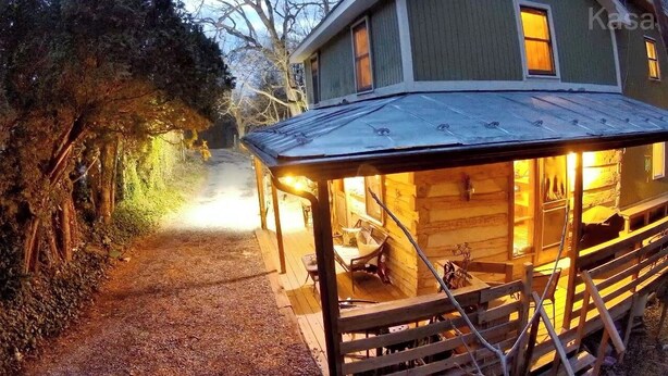 Une cabane en bois avec une véranda, une table et des chaises à l’intérieur.