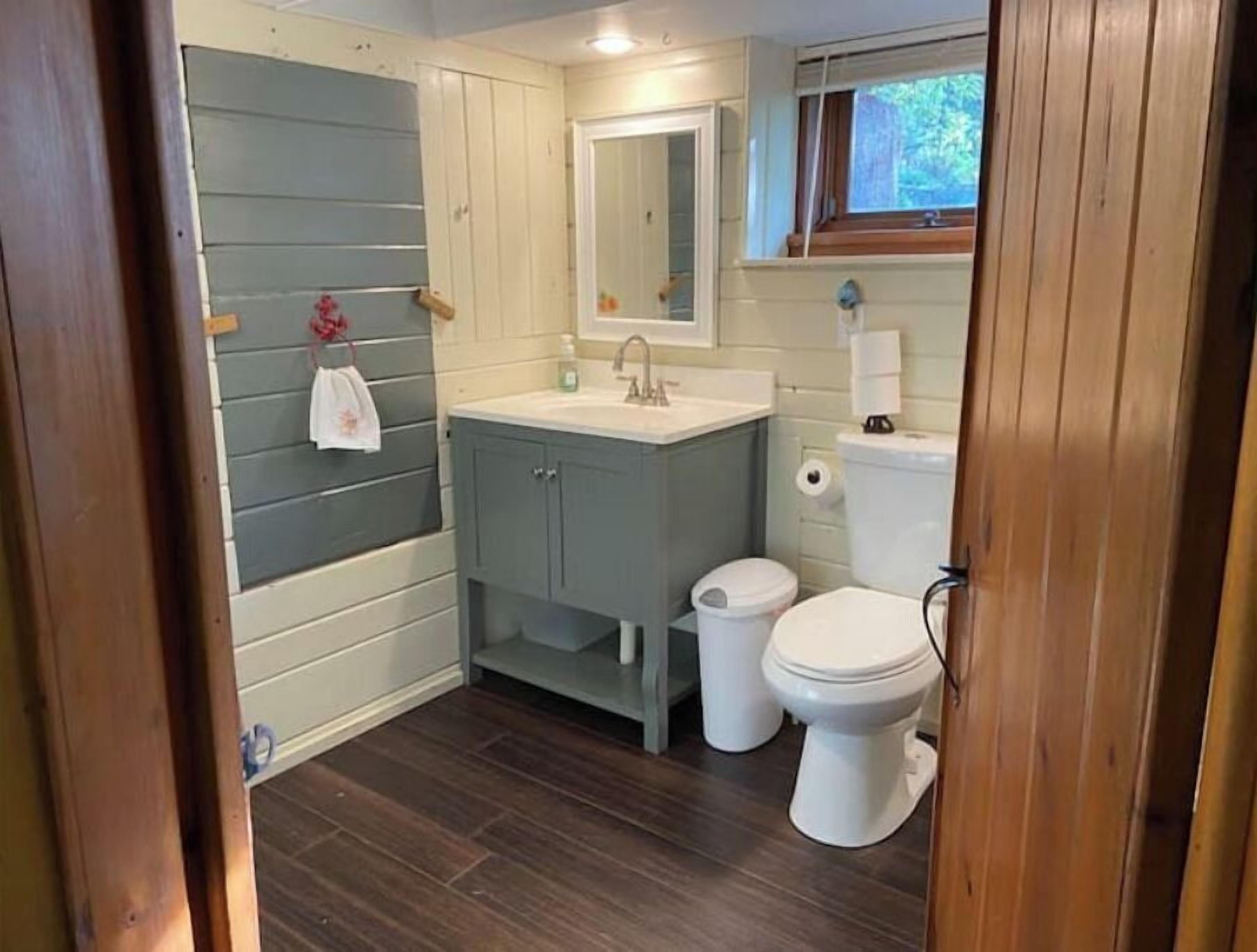 A compact bathroom with a sink, mirror, and two toilets.