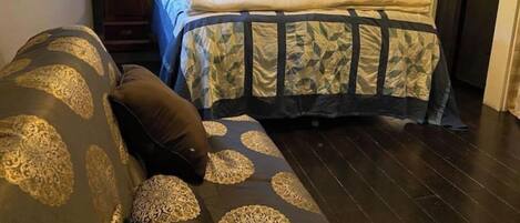 Un dormitorio con una cama, una mesita de noche, una lámpara y un ventanal con cortinas.