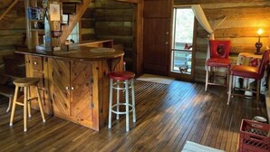 L’intérieur d’un chalet rustique, avec un bar en bois, des tabourets et un coin salon confortable.