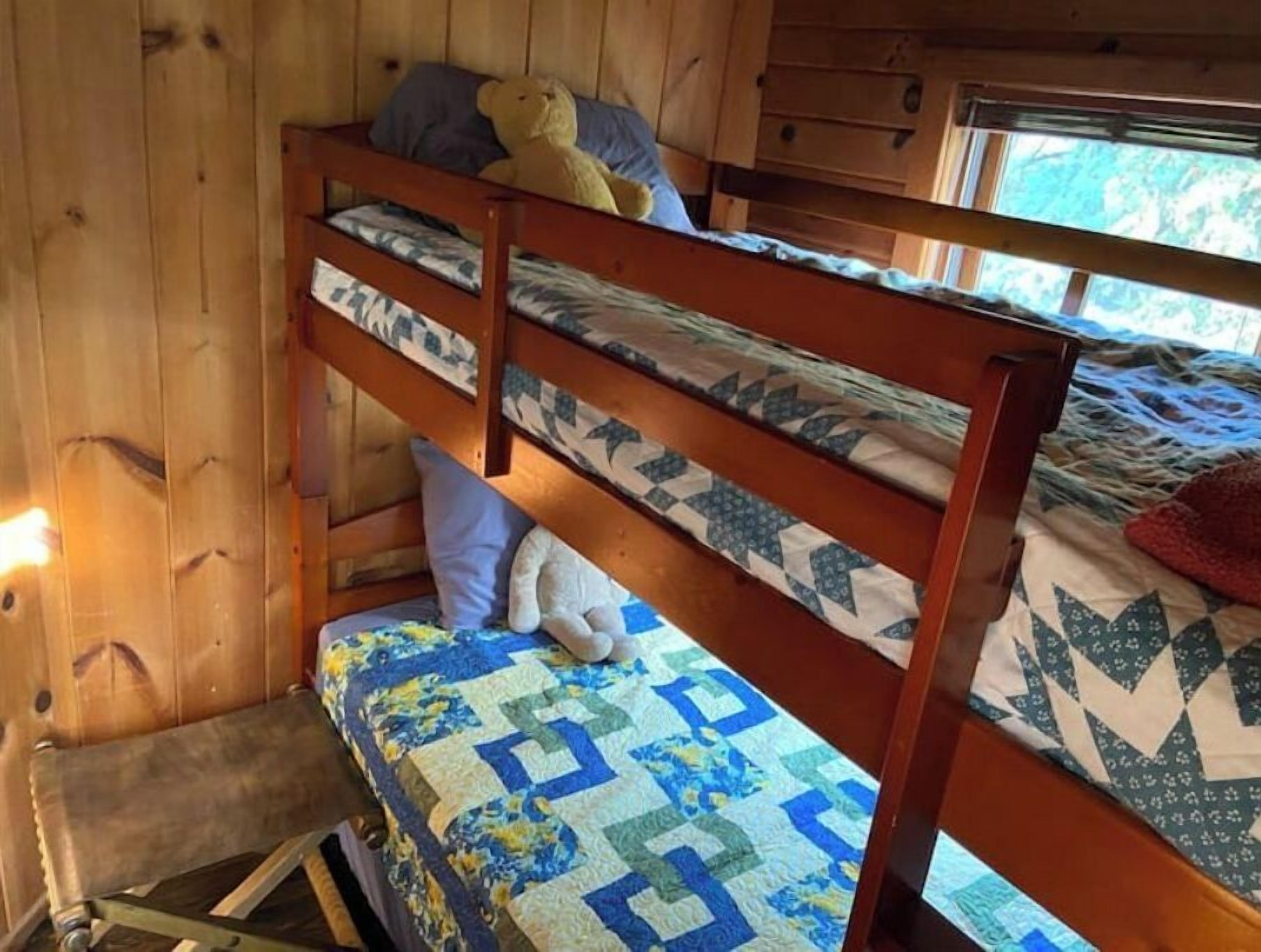 A bunk bed room with wooden walls and a window.