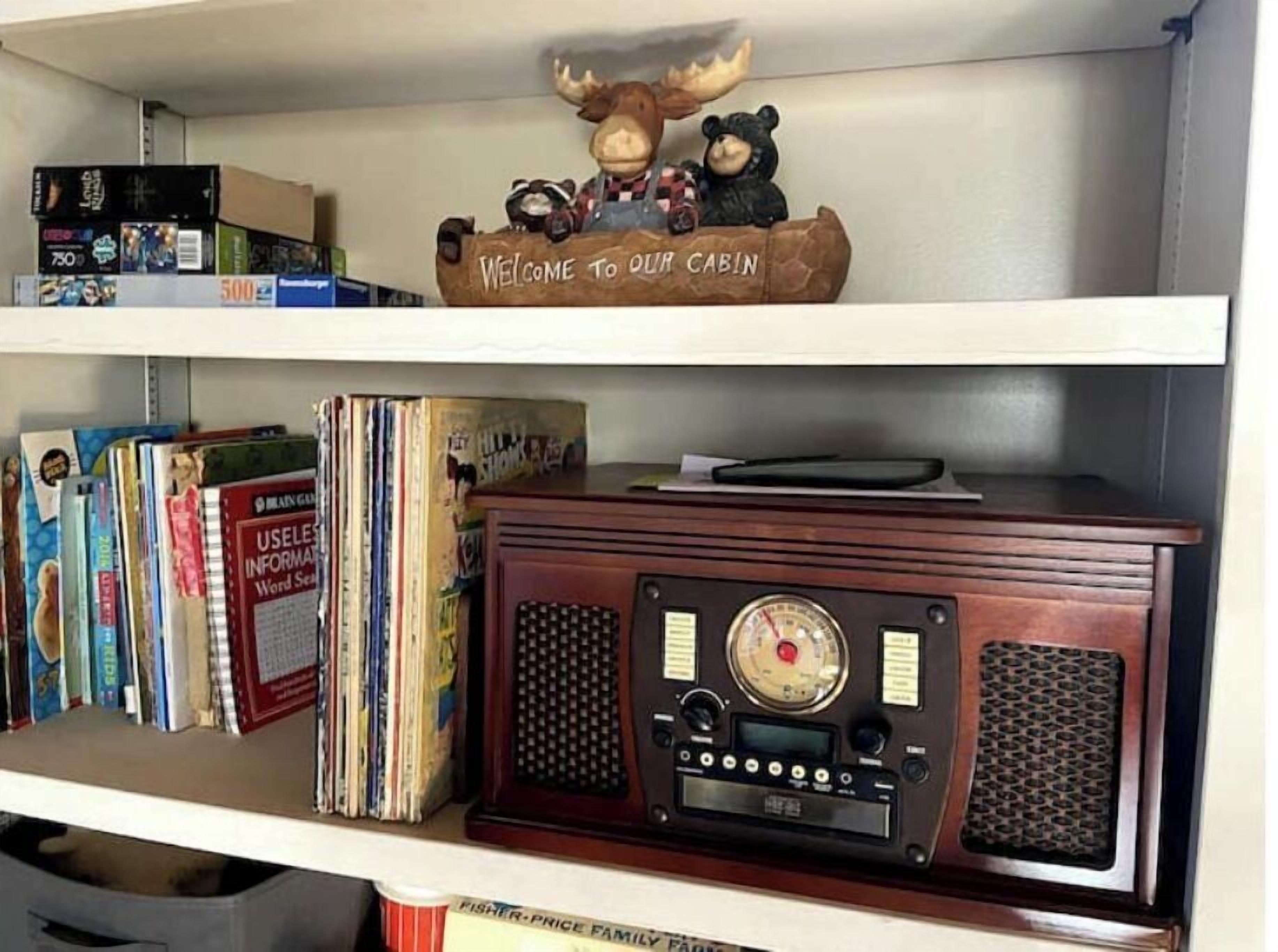 A shelf with a wooden sign reading "Welcome to our cabin," a radio, and various books.