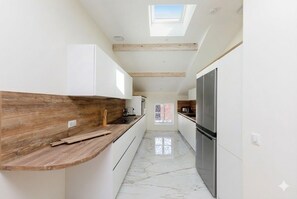 Eine moderne Küche mit weißen Schränken, einer Holz Arbeitsplatte und einem Oberlicht.
