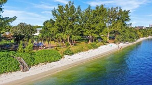 A beach with a wooden walkway leading to the shore, surrounded by lush greenery and trees. - 3 Bed, 2 Bath - North Palm Beach! (North Palm Beach)