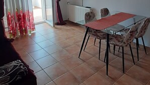 Una stanza con un tavolo da pranzo, sedie, una televisione e un termosifone.