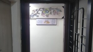 Ein Hotel Eingang mit einem 'Hotel' Schild über der Tür, einem Willkommensschild und einem dekorativen Blumenarrangement darüber.