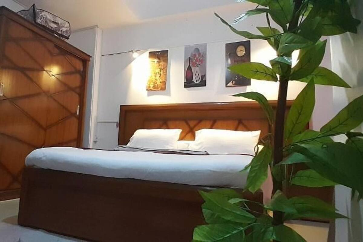 A bedroom with a bed, wardrobe, and a small refrigerator.