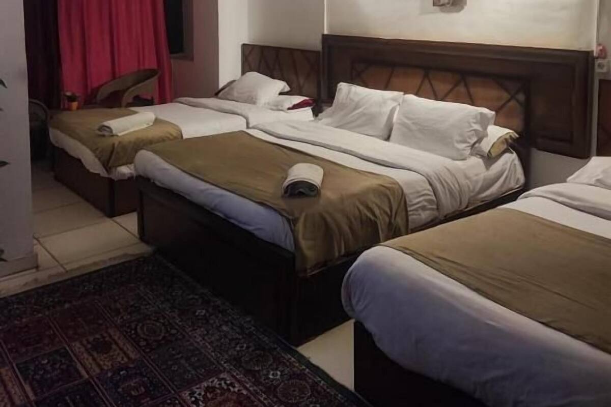 A hotel room with two beds, a red curtain, a patterned rug, and a ceiling fan.