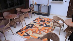 Ein Zimmer mit Korbmöbeln, einem gemusterten Teppich und einer kleinen Vitrine mit Figuren.