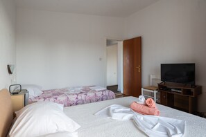 Habitación de hotel con dos camas, televisión, escritorio y armario.