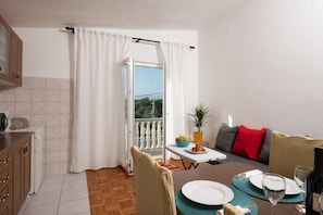 Un comedor con una mesa dispuesta para dos, una planta en maceta y vistas al balcón.