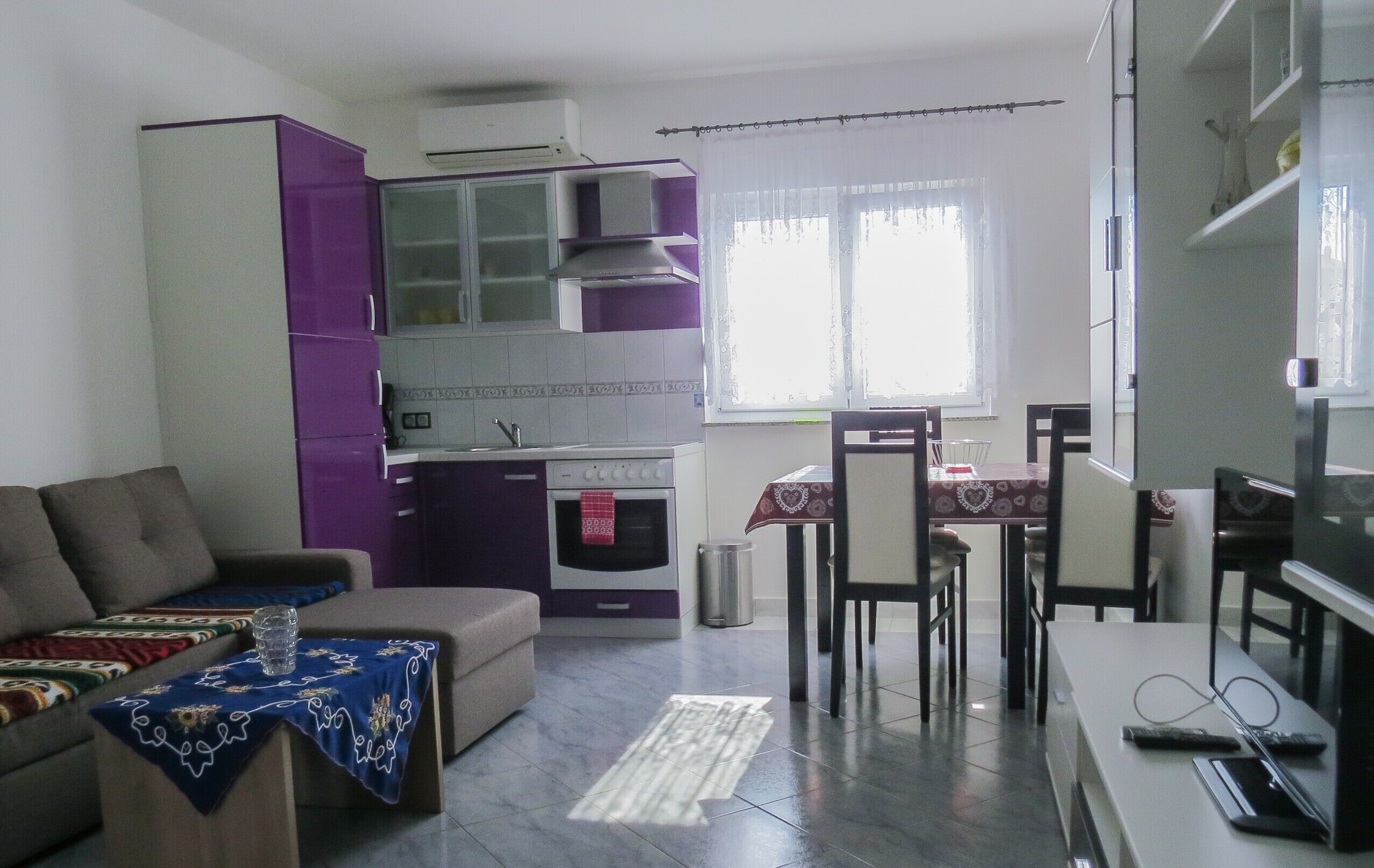 Un espacio habitable compacto con kitchenette, comedor y zona de estar.