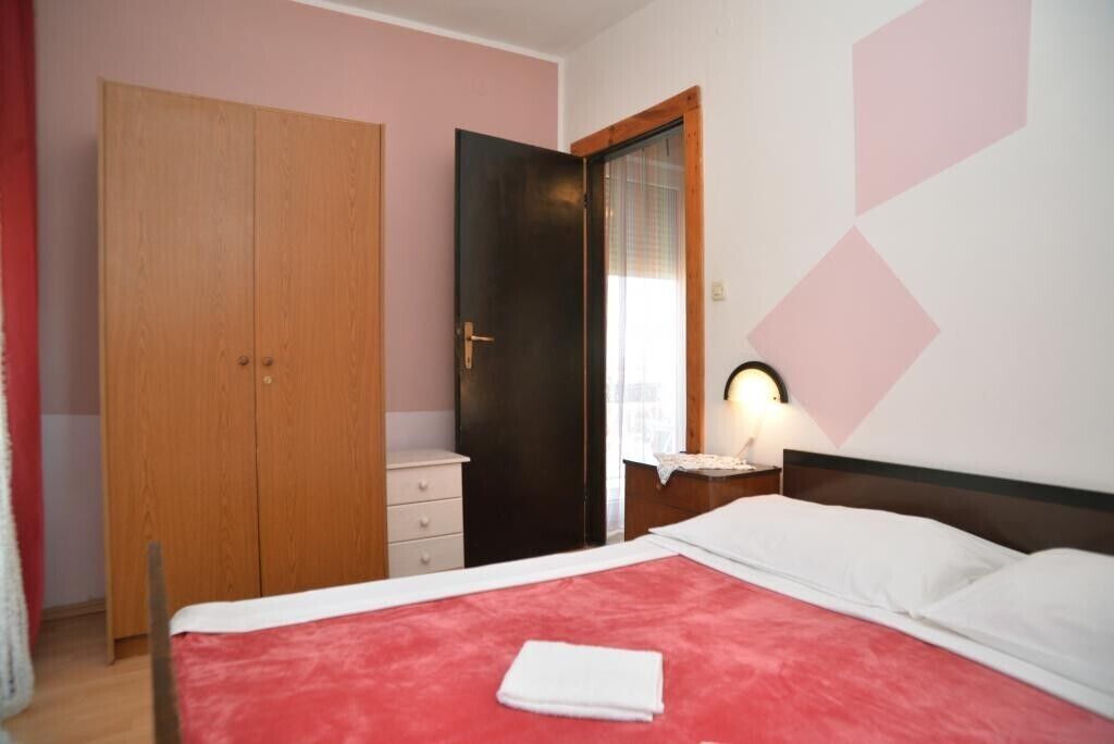 A bedroom with a bed, a wardrobe, a nightstand, and a mirror.