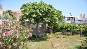 Puutarha, jossa on pergola, kukkivia kasveja ja kivimuuri.