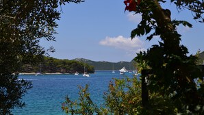Un paysage côtier avec des bateaux sur une eau calme, entouré de verdure et de collines.