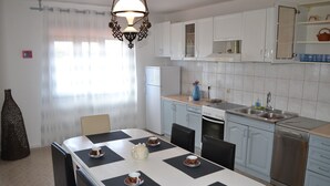Une cuisine moderne avec des meubles blancs, une table à manger avec des sets de table noirs et une table basse.