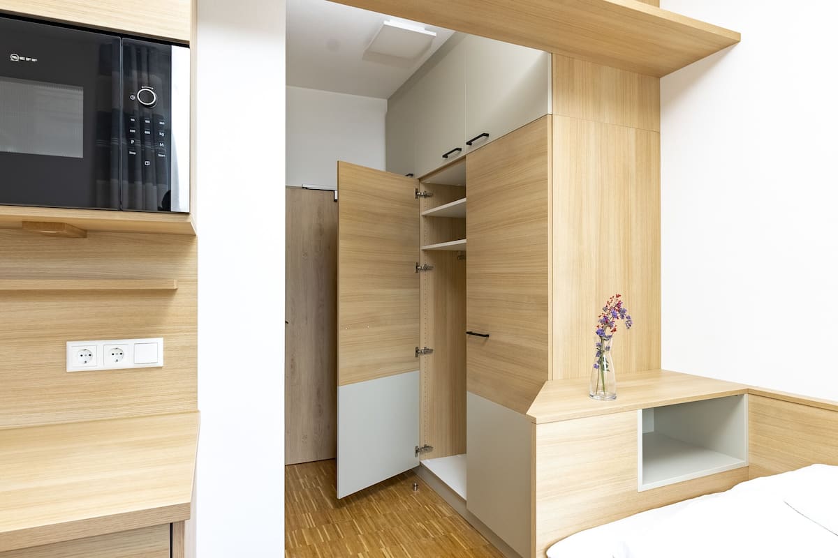 Un dormitorio moderno con armario empotrado, mesita de noche y microondas.
