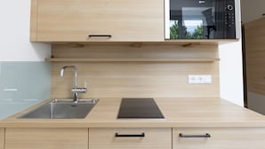 Una cocina moderna con un lavamanos de acero inoxidable, armarios de madera y un horno empotrado.