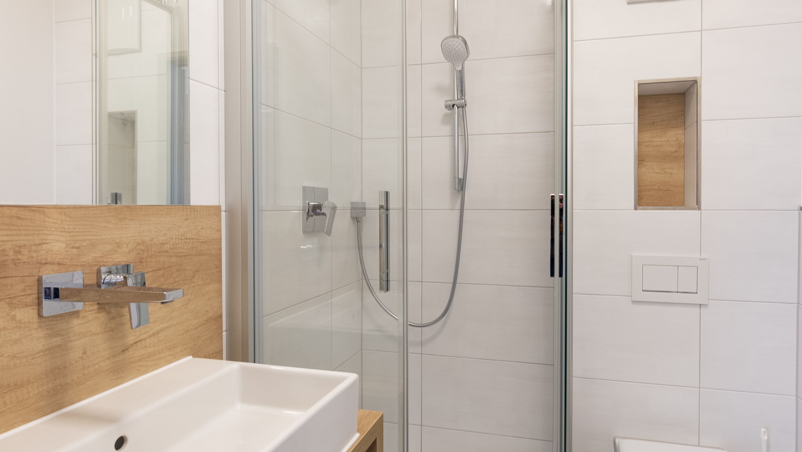 Een moderne badkamer met een glazen douchecabine, een houten wastafelmeubel en een witte wasbak.