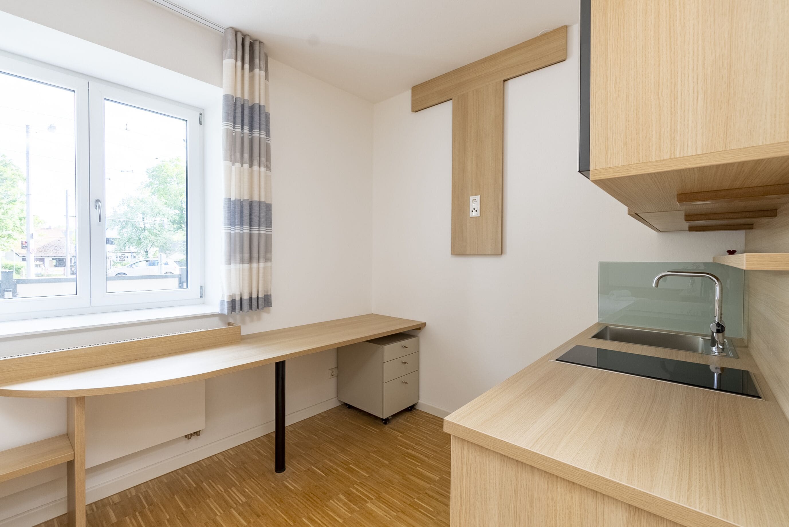 Une cuisine moderne avec un plan de travail en bois, un évier encastré et une fenêtre avec des rideaux.