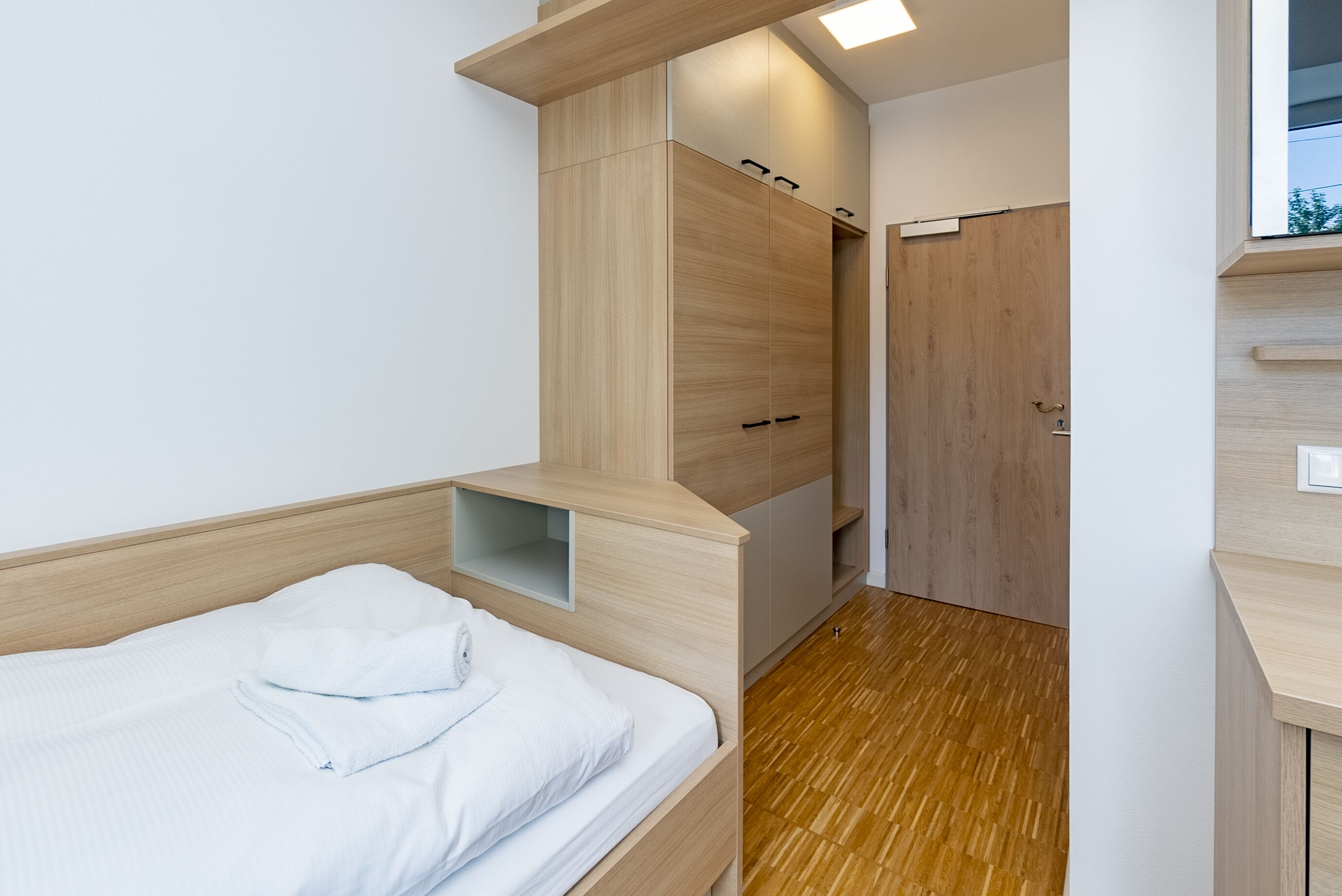 Un dormitorio pequeño con cama, armario de madera y una estantería.