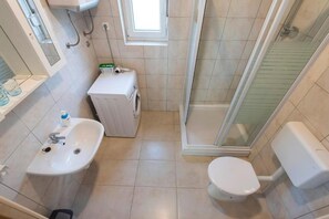 A compact bathroom with a sink, toilet, and a small washing machine. - Apartments Ema - One Bedroom Apartment with Balcony (A1) (Zadar)