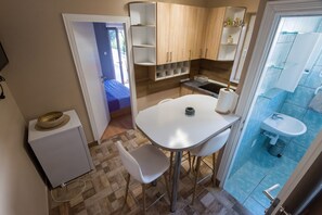 Une cuisine de taille réduite avec une table blanche, un petit réfrigérateur et un évier.