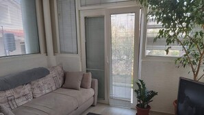 A living room with a sofa, a TV, a potted plant, and a sliding glass door. - Apartments Branka - Two Bedroom Apartment with Terrace (Razanac)