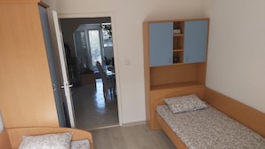 A small, compact room with two single beds, a wooden wardrobe, and a small cabinet. - Apartments Branka - Two Bedroom Apartment with Terrace (Razanac)