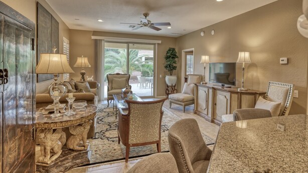 A spacious living room with a large TV, comfortable seating, and a ceiling fan.