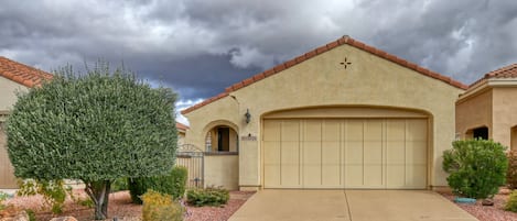 A residential house with a beige facade, a red-tiled roof, and a garage.