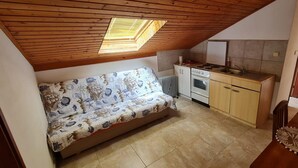 Eine kompakte Küche mit Einbauherd, Kühlschrank und Holzbalkendecke mit Oberlichtern.
