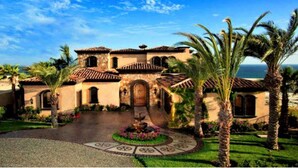 A Mediterranean-style building with a central courtyard, palm trees, and a view of the ocean. - ULTIMATE LUXURY OCEANVIEW CABO HOME W/PRIVATE POOL & GOLF. NOVAISPANIA (Cabo San Lucas)