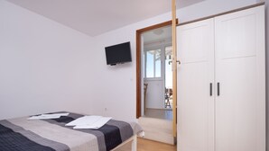 Ein Schlafzimmer mit einem Bett, einem an der Wand befestigten Fernseher und einem Kleiderschrank.