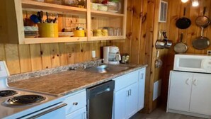A kitchen with wooden cabinets, a granite countertop, a dishwasher, a stove, and a microwave. - Belgrade Lakes McGrath Pond (Oakland)