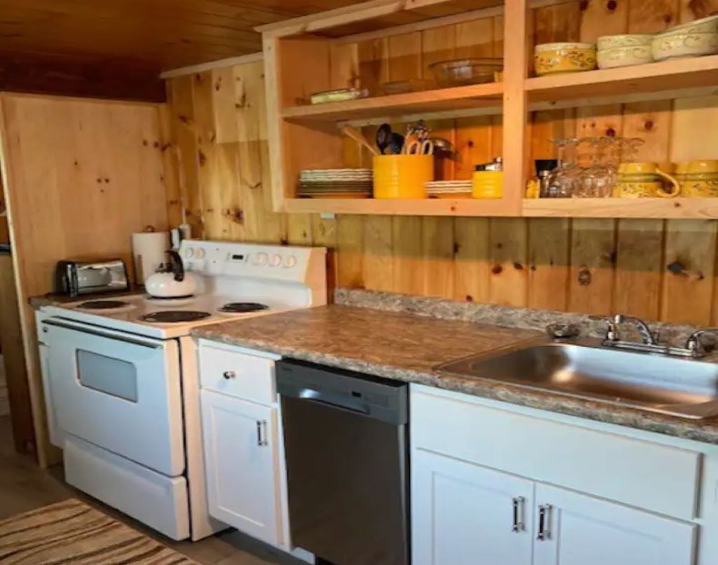 A kitchen with white cabinets, a granite countertop, a stainless steel sink, and a white stove.