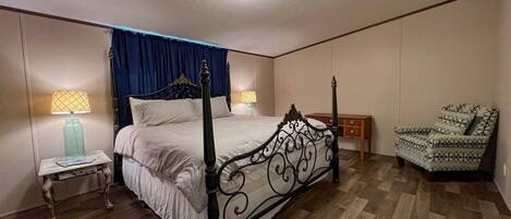 Une chambre à coucher avec un lit à baldaquin, une table de chevet avec une lampe, une chaise et un plancher en bois.