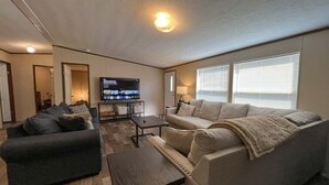 Ein Wohnzimmer mit zwei Sofas, einem Couchtisch, einem Fernseher und einem Kamin.