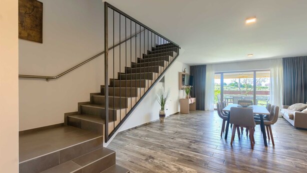 A modern interior with a staircase, a dining area with a table and chairs, and a view through a large window. - Brand New Modern apartment for 6+2 guests with shared pool (Novigrad)