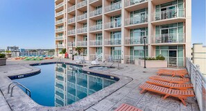 Relax by the rooftop pool surrounded by a deck and lounge chairs, with a hot tub nearby.