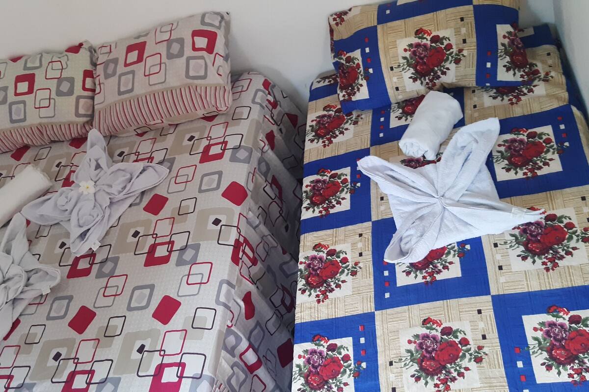 Un lit avec une couvre-lit à motifs géométriques et une autre couvre-lit matelassée à motifs floraux.